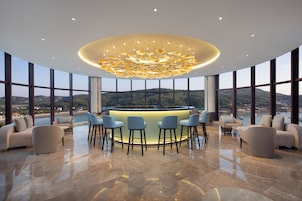 A modern bar area with a central island, seating, and a view of the landscape.