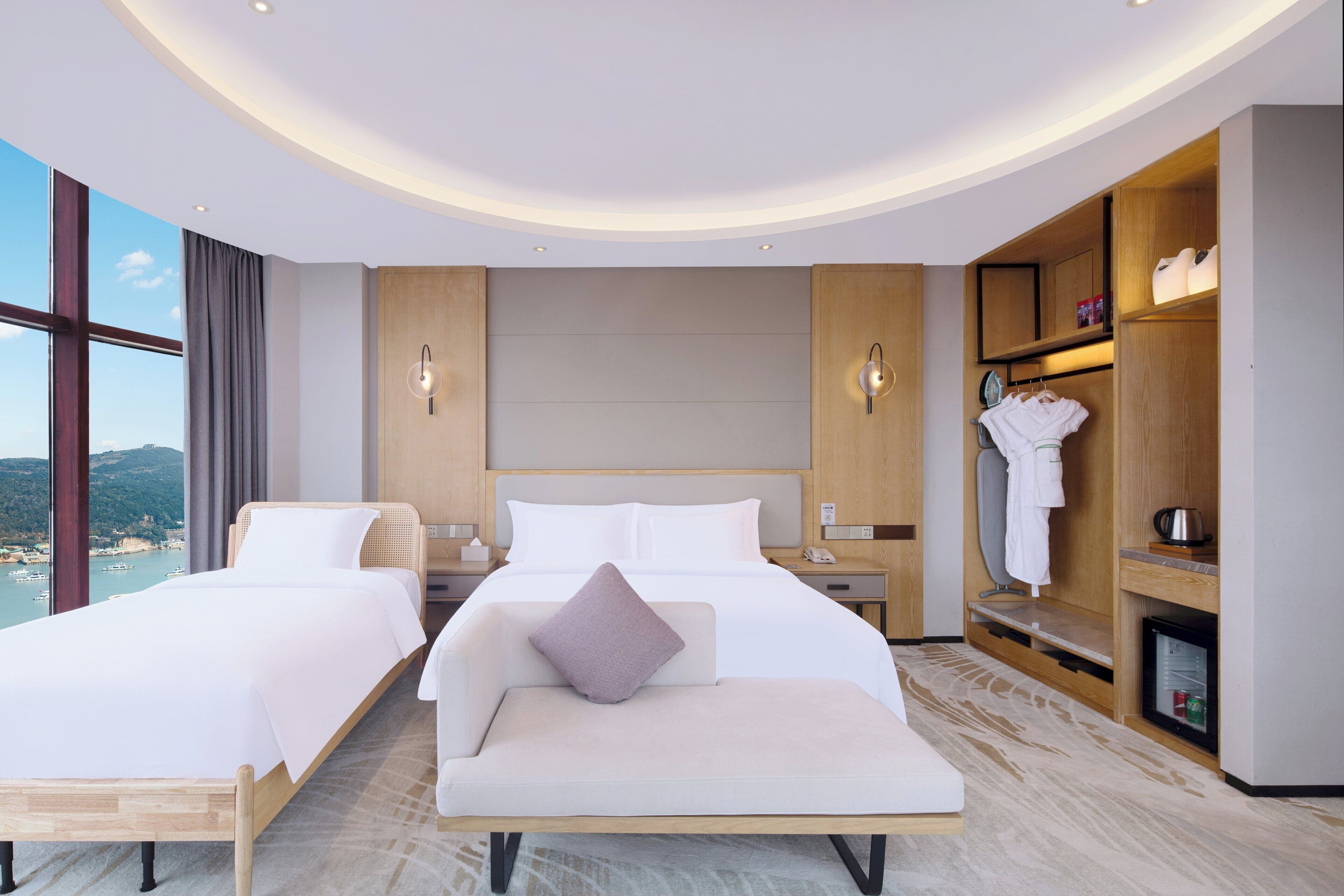 A hotel room with a large bed, a sofa, a wardrobe, and a view of the sea.