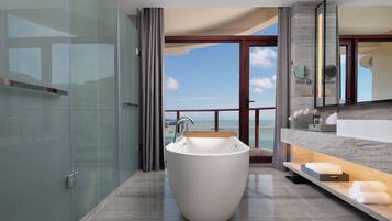 Une salle de bain moderne avec une baignoire sur pieds, une douche à parois de verre et une vue sur la mer.