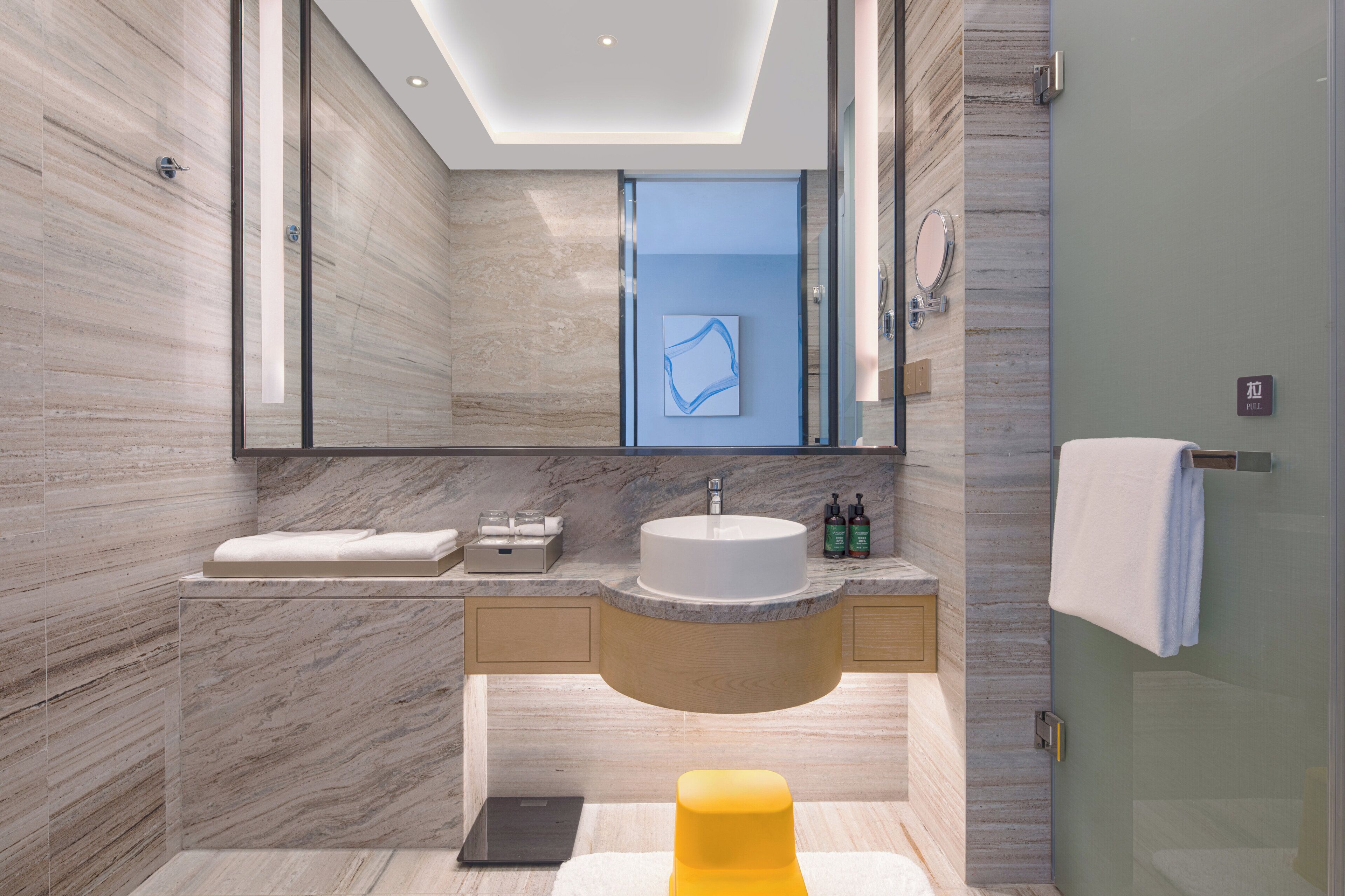 Un baño moderno con tocador de mármol, un espejo grande y una cabina de ducha de vidrio.