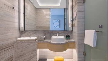 Un baño moderno con tocador de mármol, un espejo grande y una cabina de ducha de vidrio.