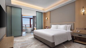 Una habitación de hotel moderna con una cama grande, una mesita de noche y vistas al exterior.