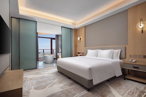 Une chambre d’hôtel moderne avec un grand lit, une table de chevet, une commode et une vue sur l’extérieur.