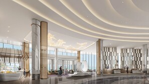 Een ruime lobby met een modern ontwerp, met een receptiebalie, zithoeken en een groot decoratief plafond.