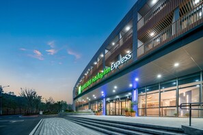 A Holiday Inn Express hotel with a modern design, featuring a prominent entrance and a well-lit facade. - Holiday Inn Express Nanjing Happy Valley by IHG (Nanjing)