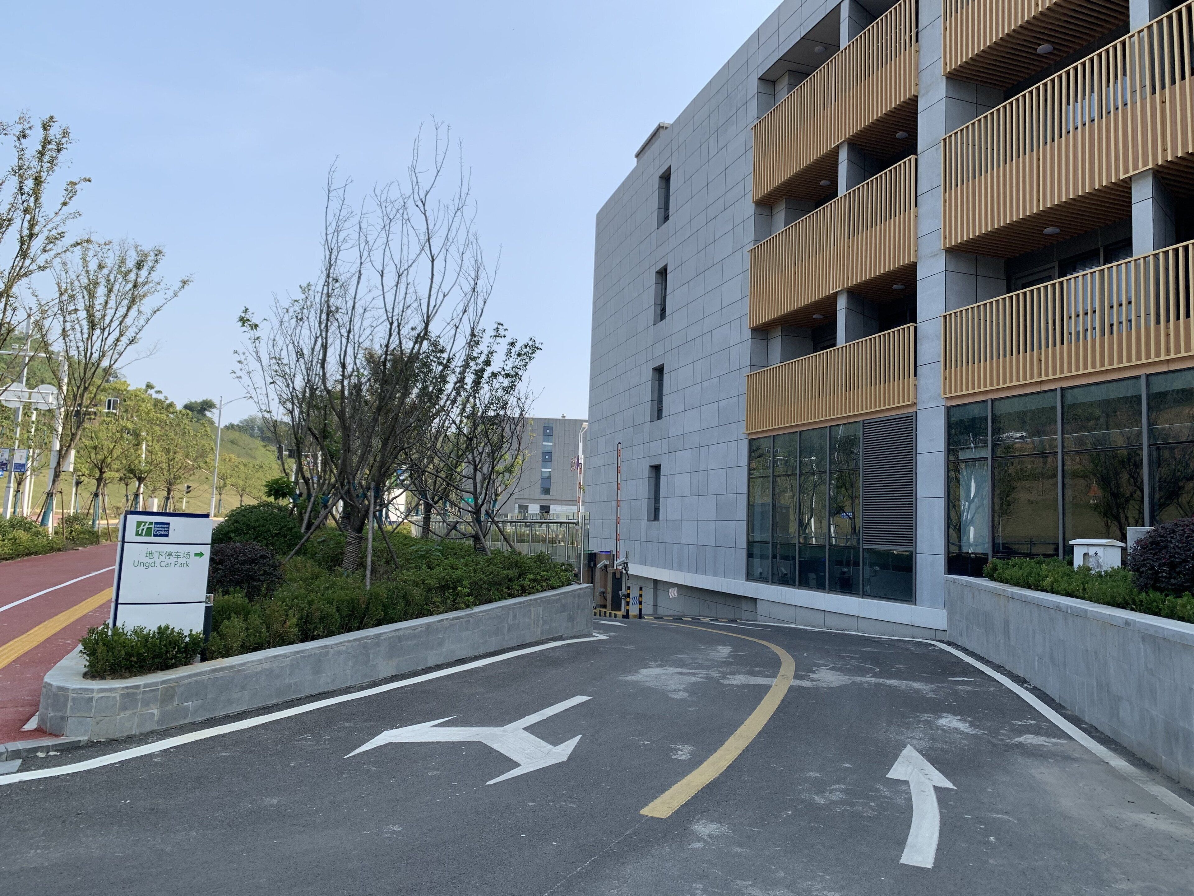 Um edifício moderno com área de estacionamento, setas de sinalização e um aviso indicando estacionamento de carros.