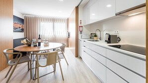 A modern kitchen with a round dining table, chairs, and a coffee machine. - GuestReady - Tigerlily (Porto)