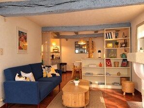 Ein Wohnzimmer mit einem blauen Sofa, einem Holztisch, einem Bücherregal und einer Sukkulenten-Dekoration.