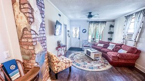 A living room with a red sofa, a wooden coffee table, and a patterned rug. - Charming Centennial Cottage-Downtown! (Rapid City)