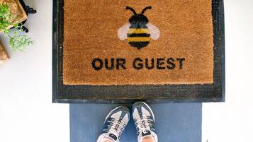 A doormat with a bee design and the words "OUR GUEST" on a blue floor.