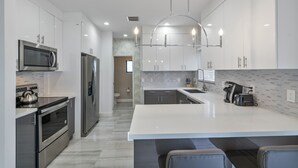 A modern kitchen with stainless steel appliances, a large island, and a pendant light. - New Townhome near Wilton Manors/Las Olas (Fort Lauderdale)