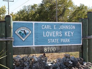 Un panneau en bois portant l’inscription « Carl E. Johnson Lovers Key State Park 8700 » et le logo du service des parcs de Floride.