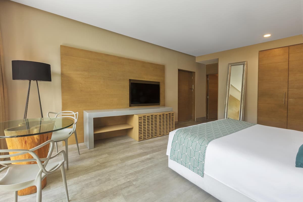A hotel room with a bed, a desk with a TV, a chair, and a wardrobe.