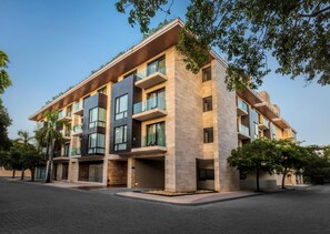 A modern multi-story building with balconies, large windows, and a paved ground floor. - The Yucatan Playa del Carmen, Tapestry Collection by Hilton (Playa del Carmen)