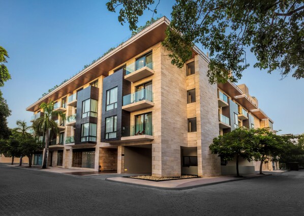 A modern multi-story building with balconies, large windows, and a paved ground floor. - The Yucatan Playa del Carmen, Tapestry Collection by Hilton (Playa del Carmen)