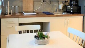 A compact kitchen with white cabinetry, a coffee machine, and a hanging light fixture. - Luxury Apartments Bello (Punta Cana)