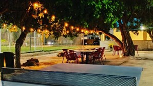 An outdoor dining area with a table and chairs, surrounded by trees and string lights. - Luxury Apartments Bello (Punta Cana)