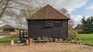 A small, dark wooden building with a triangular roof, surrounded by gravel and potted plants. - The Granary by Bloom Stays - cute lodge sleeps 2 guests  in 1 bedroom (Canterbury)