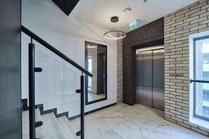 A modern interior with a staircase, a brick wall, and an elevator.