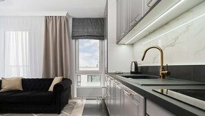 Una cocina moderna con encimera negra, grifo dorado y armarios grises.