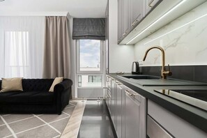 Una cocina moderna con encimera negra, grifo dorado y armarios grises.