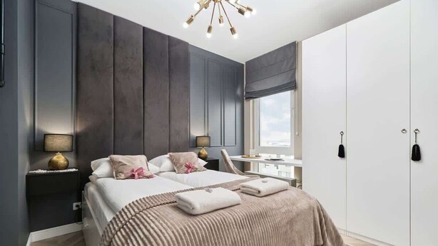 Un dormitorio con cama, mesitas de noche, ventana y armario.