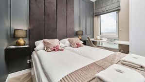 Una habitación de hotel moderna con una cama grande, mesitas de noche, un escritorio y un ventanal con vistas.