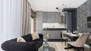 Una sala de estar moderna con un sofá negro, una mesa de centro de vidrio y un comedor con una mesa redonda y sillas.