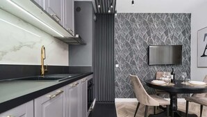 Una cocina moderna con encimera negra, grifo dorado y un comedor con mesa redonda y sillas.