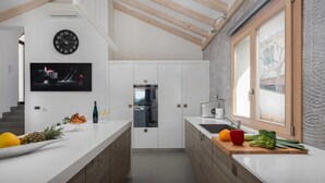 Een moderne keuken met witte kasten, een houten plafond en een groot raam.