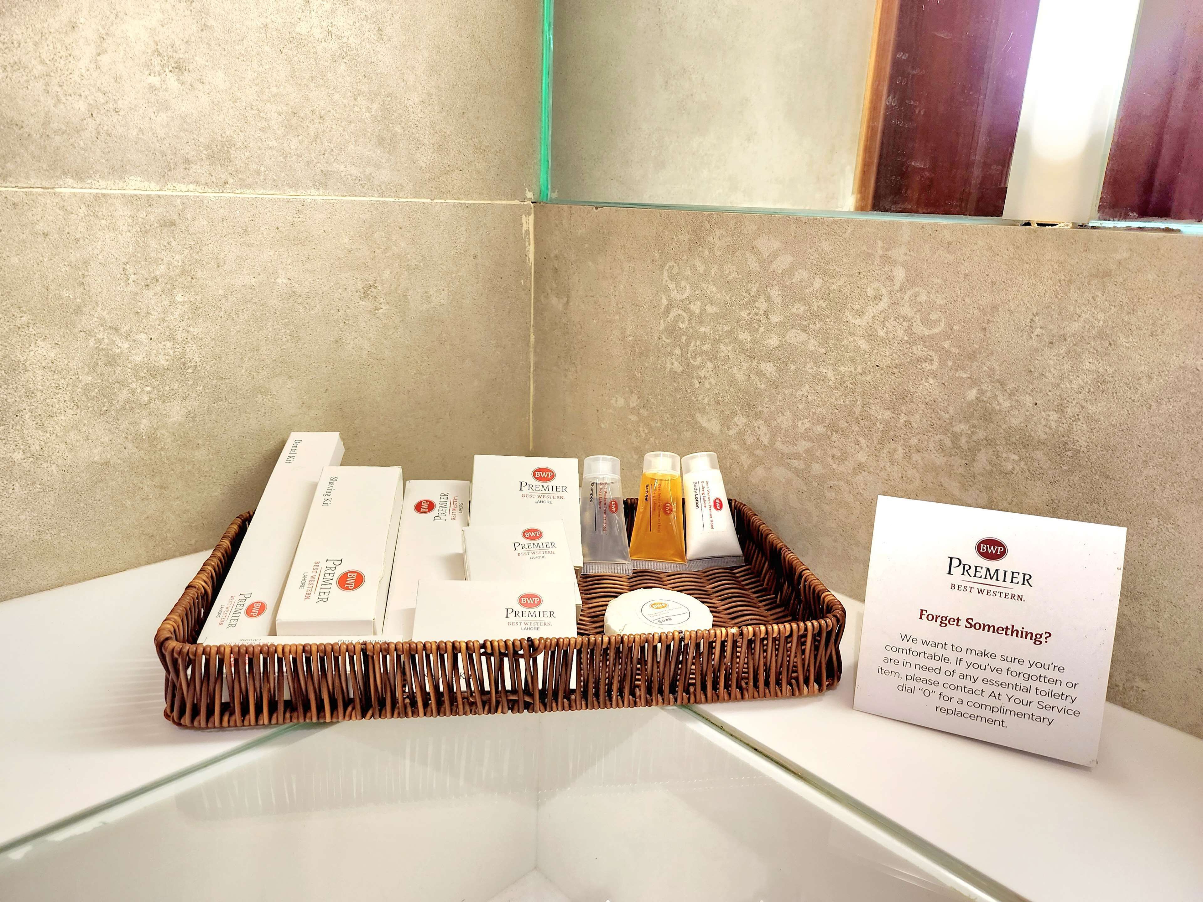 A bathroom with a wicker basket containing toiletries and a sign about complimentary toiletries.