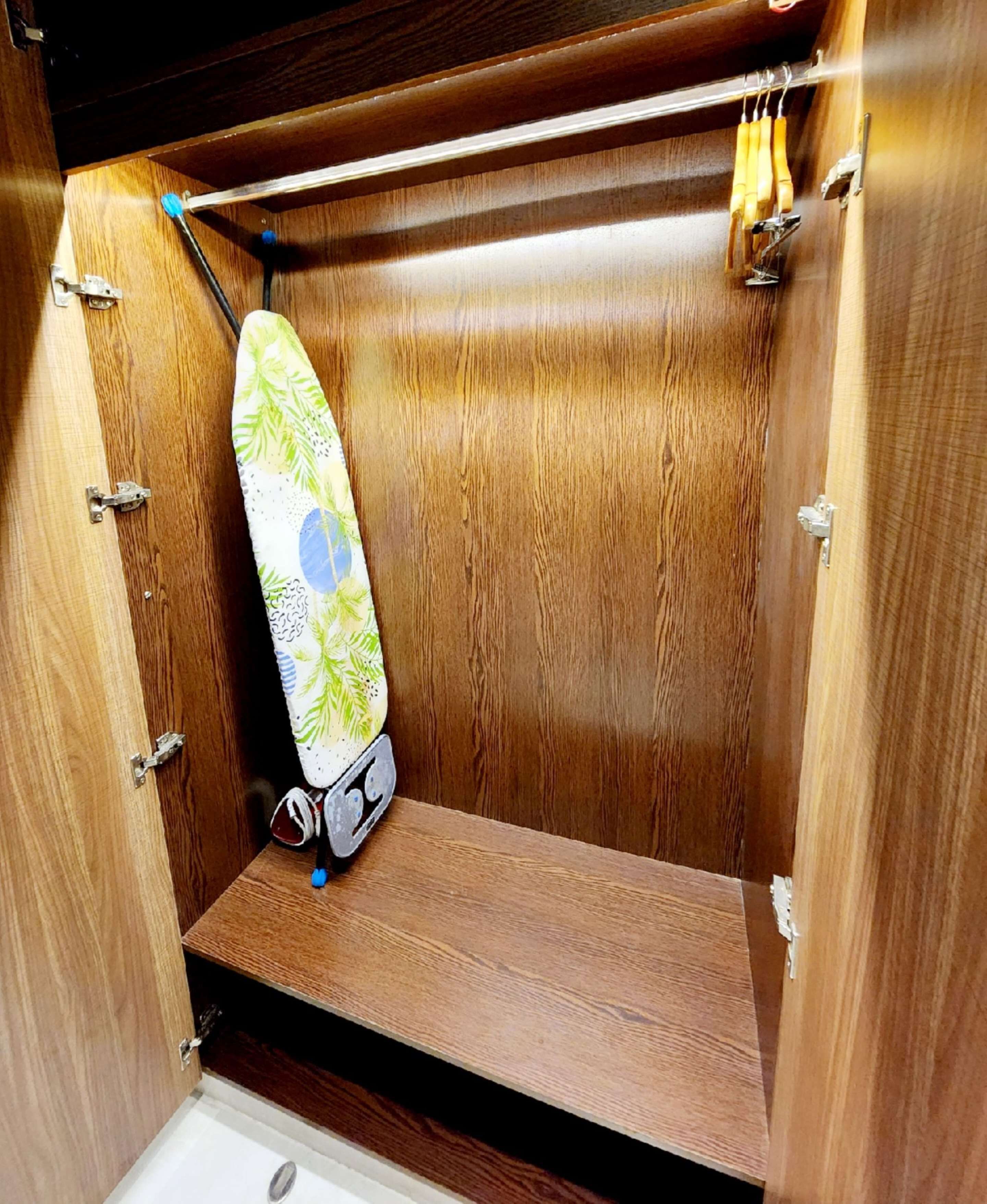 Un gabinete de madera con un estante y ganchos para colgar objetos.
