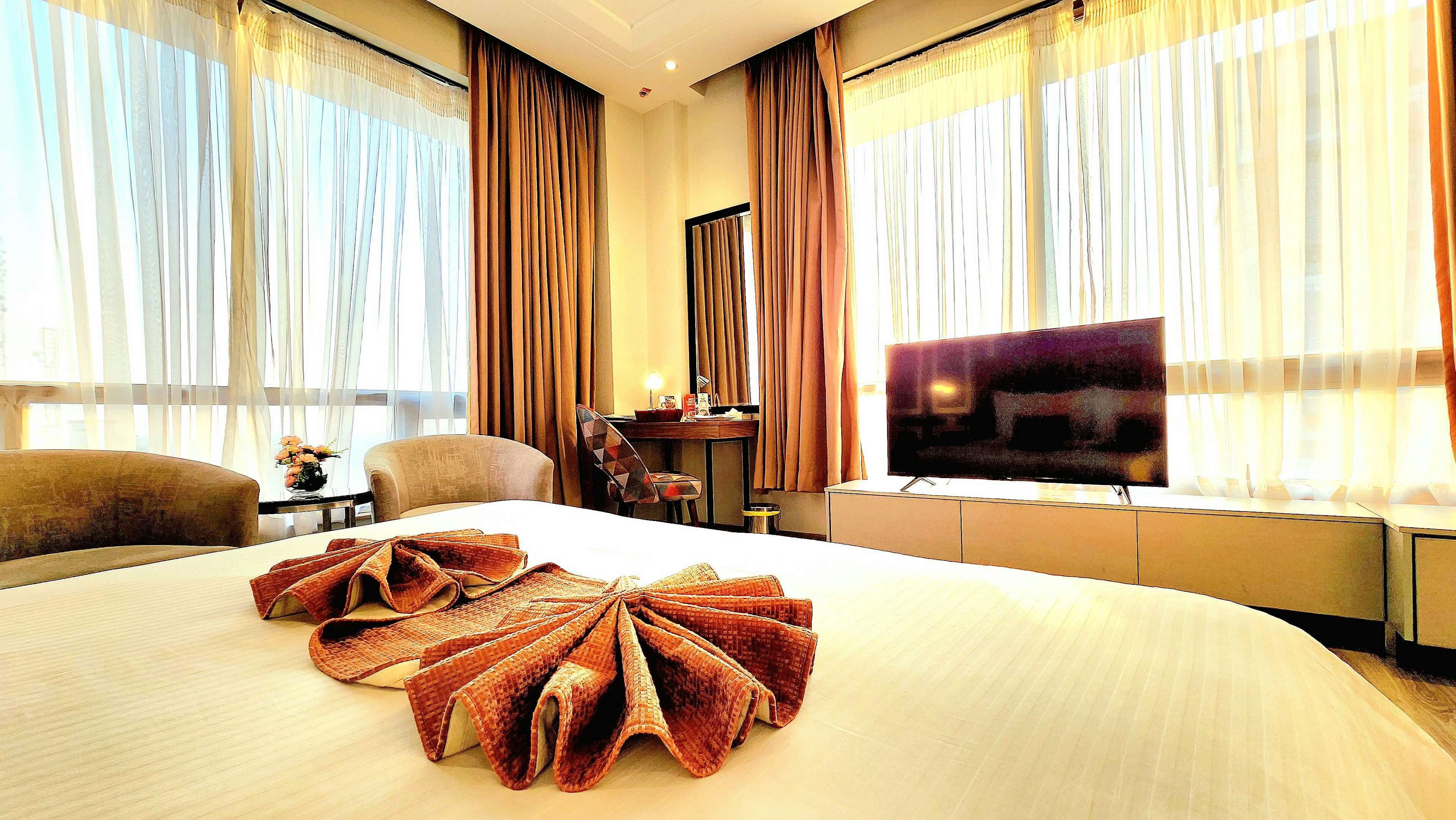 A hotel room with a large bed, a television, and curtains.