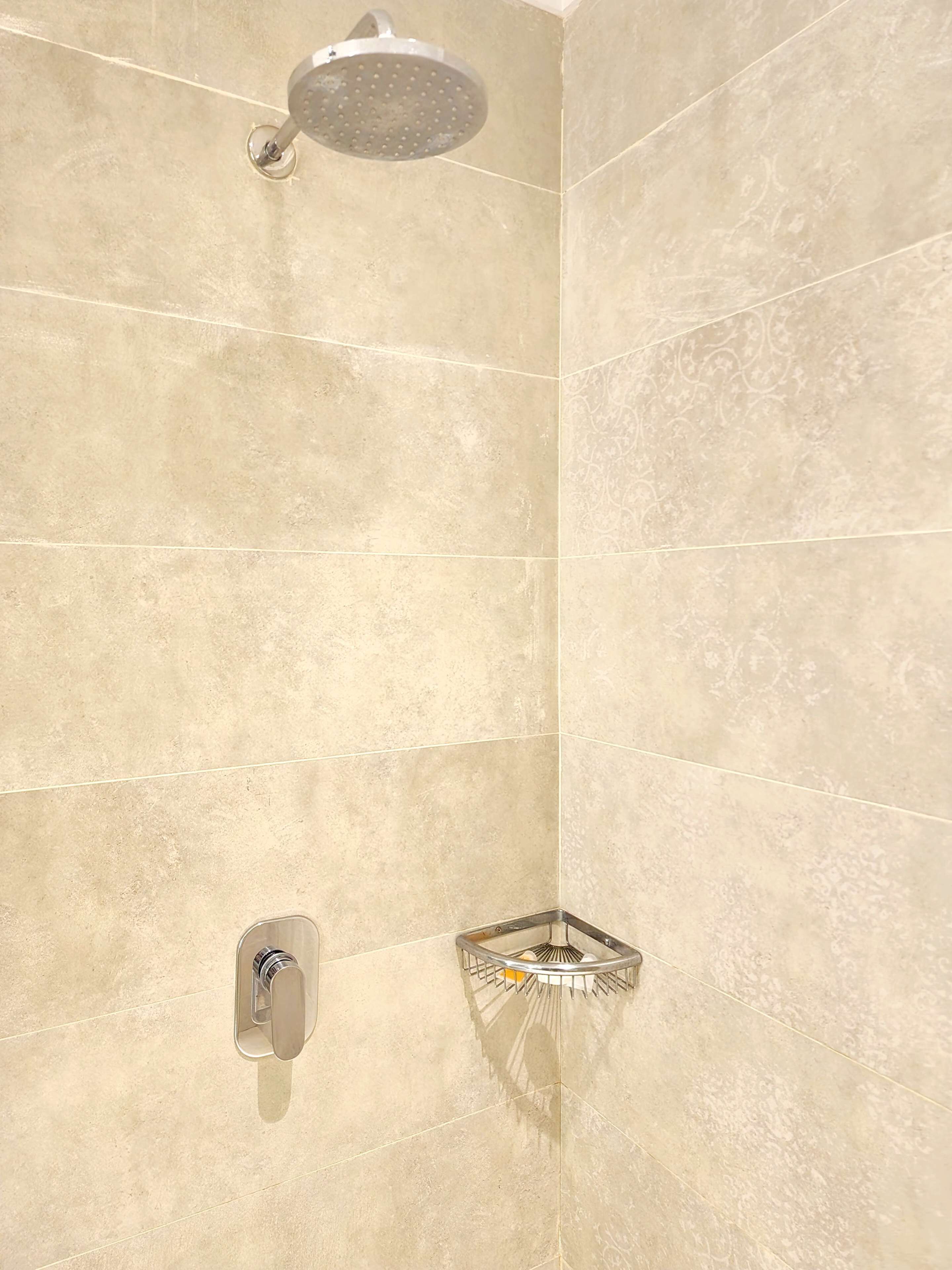 A shower with a handheld showerhead and a wall-mounted faucet.