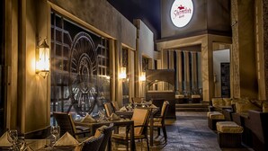 An outdoor dining area with wicker furniture, a large illuminated sign for Shandur Grill, and a decorative wall with a large wheel design. - Best Western Premier Hotel Gulberg Lahore (Lahore)