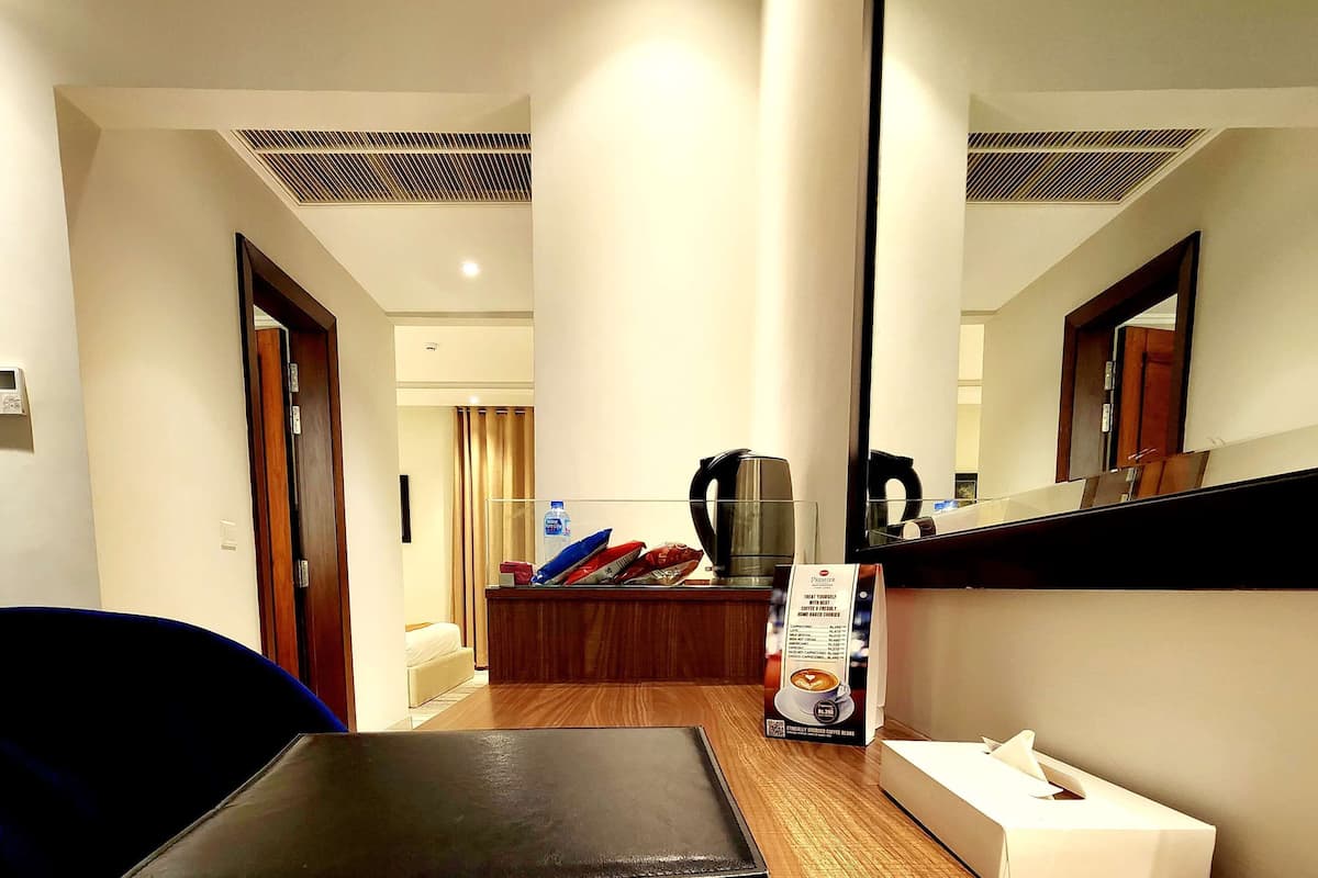 Habitación de hotel con un escritorio de madera, una carpeta de cuero negro, un menú y una caja de pañuelos.
