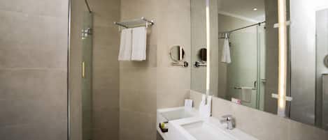 A modern bathroom with a glass shower enclosure, a white sink, and a large mirror.