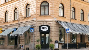 A corner building with a "RUTH" sign, featuring a classic architectural style with arched windows and a striped awning. - Hotel Ruth, WorldHotels Crafted  (Stockholm)