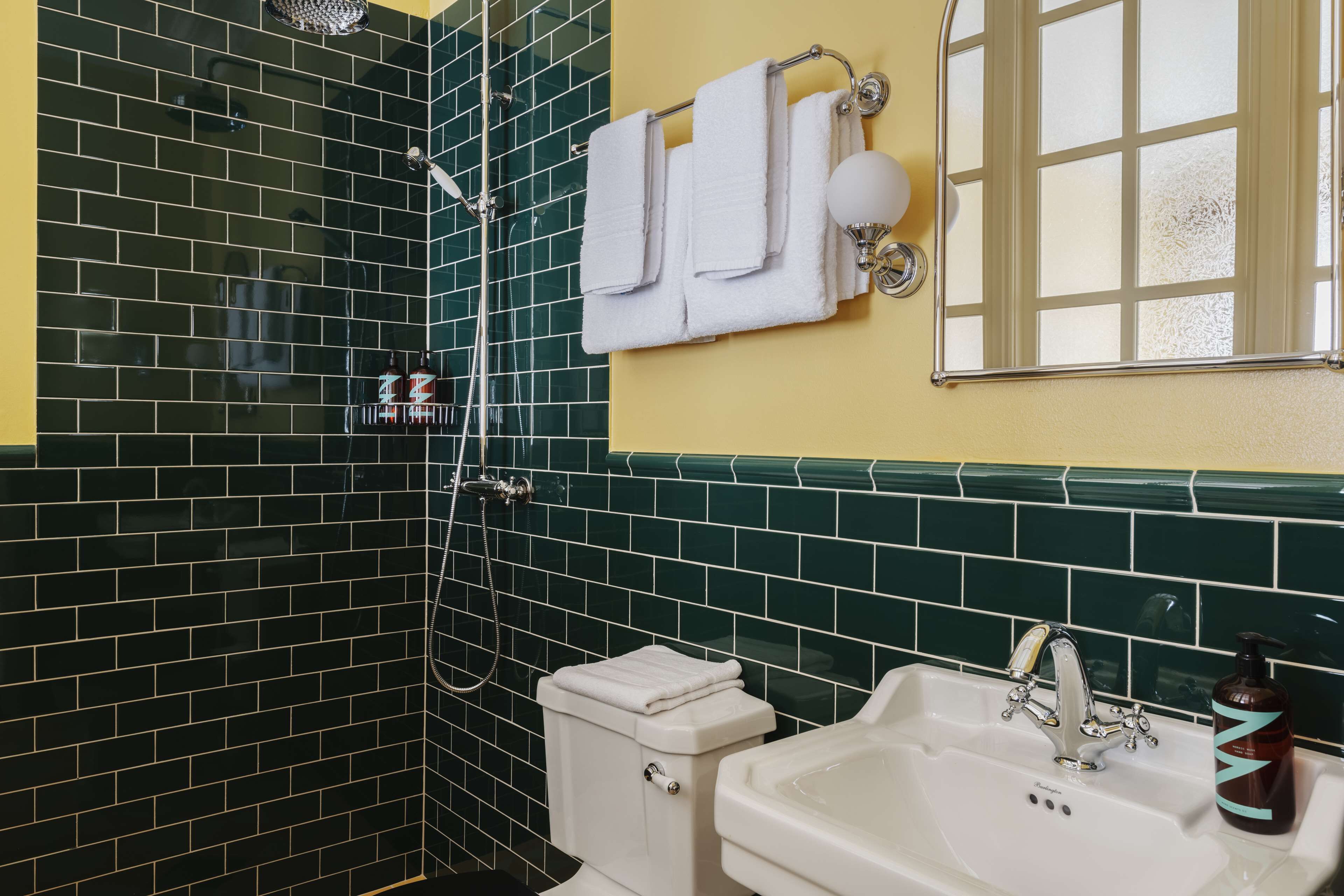 A bathroom with a shower, toilet, sink, and a towel rack with towels.