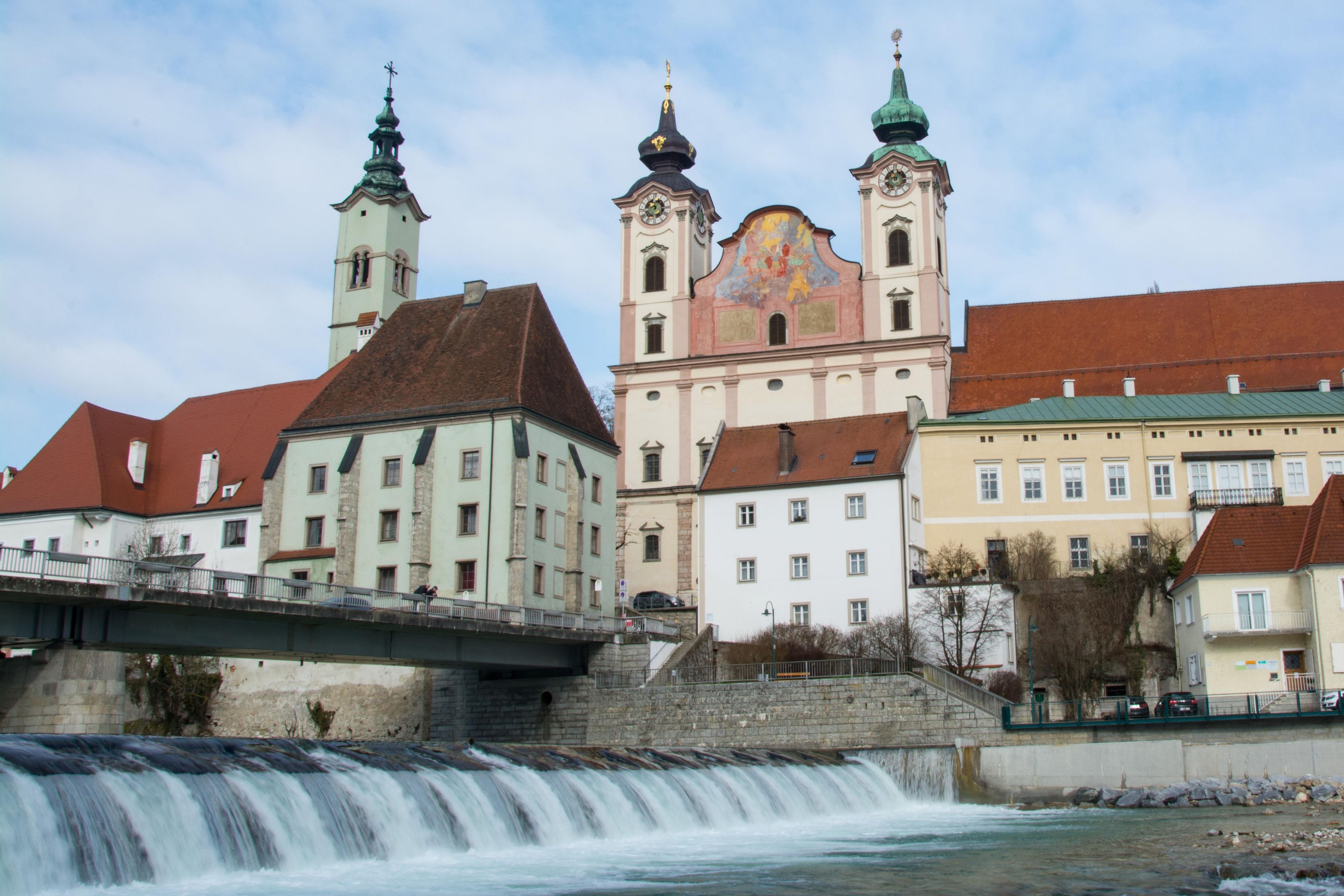 A historic building with a prominent tower and a bridge over a flowing river.