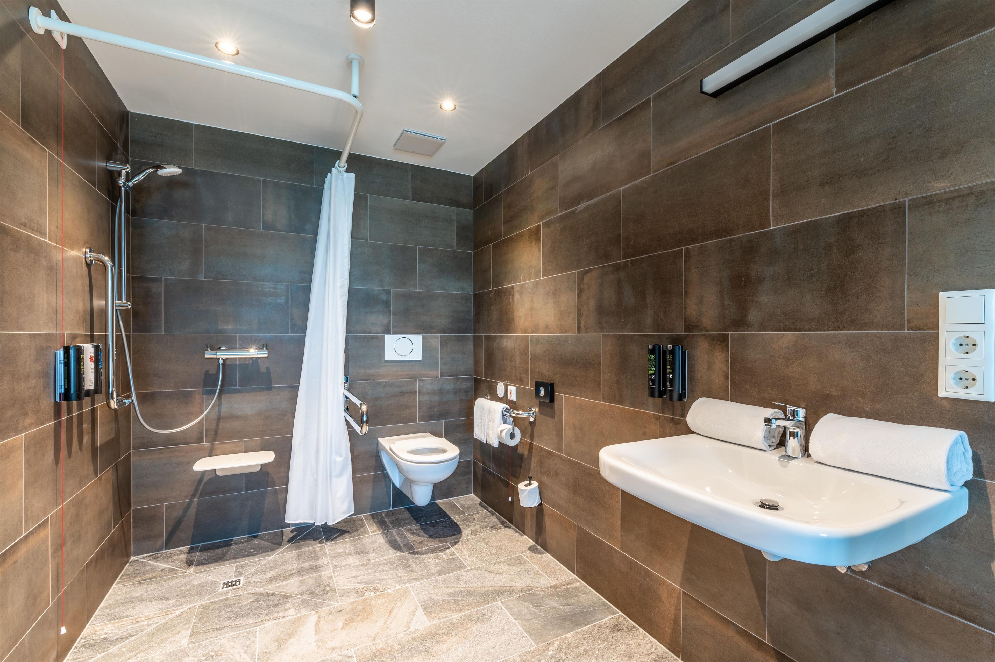 Een moderne badkamer met douche, toilet en wastafel.