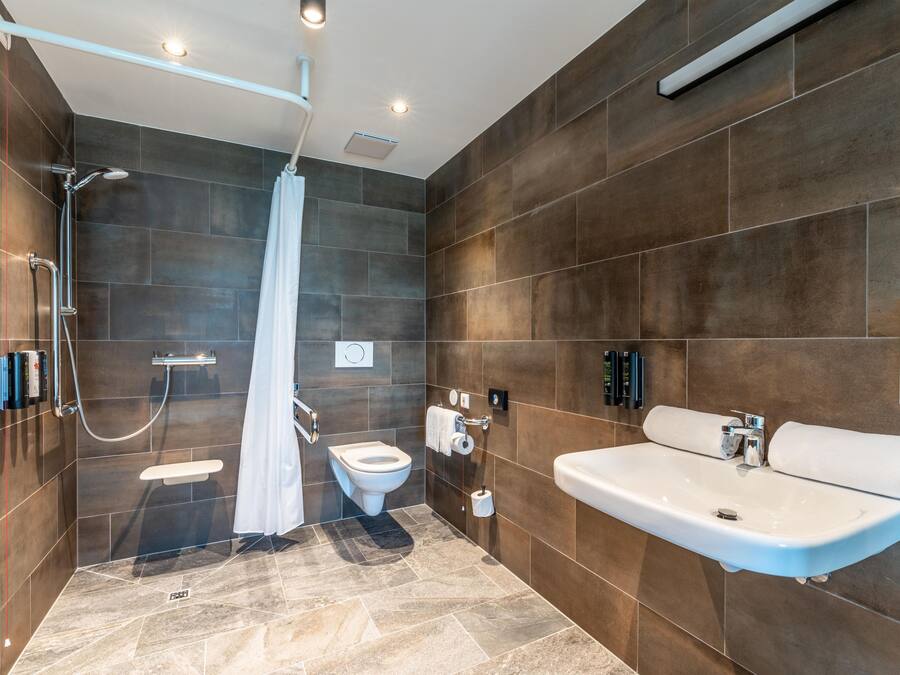 A modern bathroom with a shower, toilet, and sink.