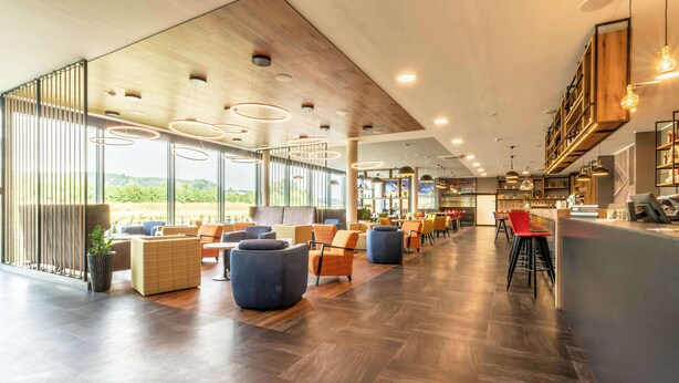 A spacious indoor area with wooden flooring, seating arrangements, and a bar area. - Aiden by Best Western Stadtgut Hotel Steyr (Steyr)