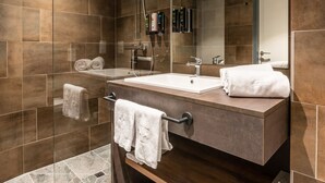 A modern bathroom with a glass-enclosed shower, a large mirror, and a wooden vanity. - Aiden by Best Western Stadtgut Hotel Steyr (Steyr)