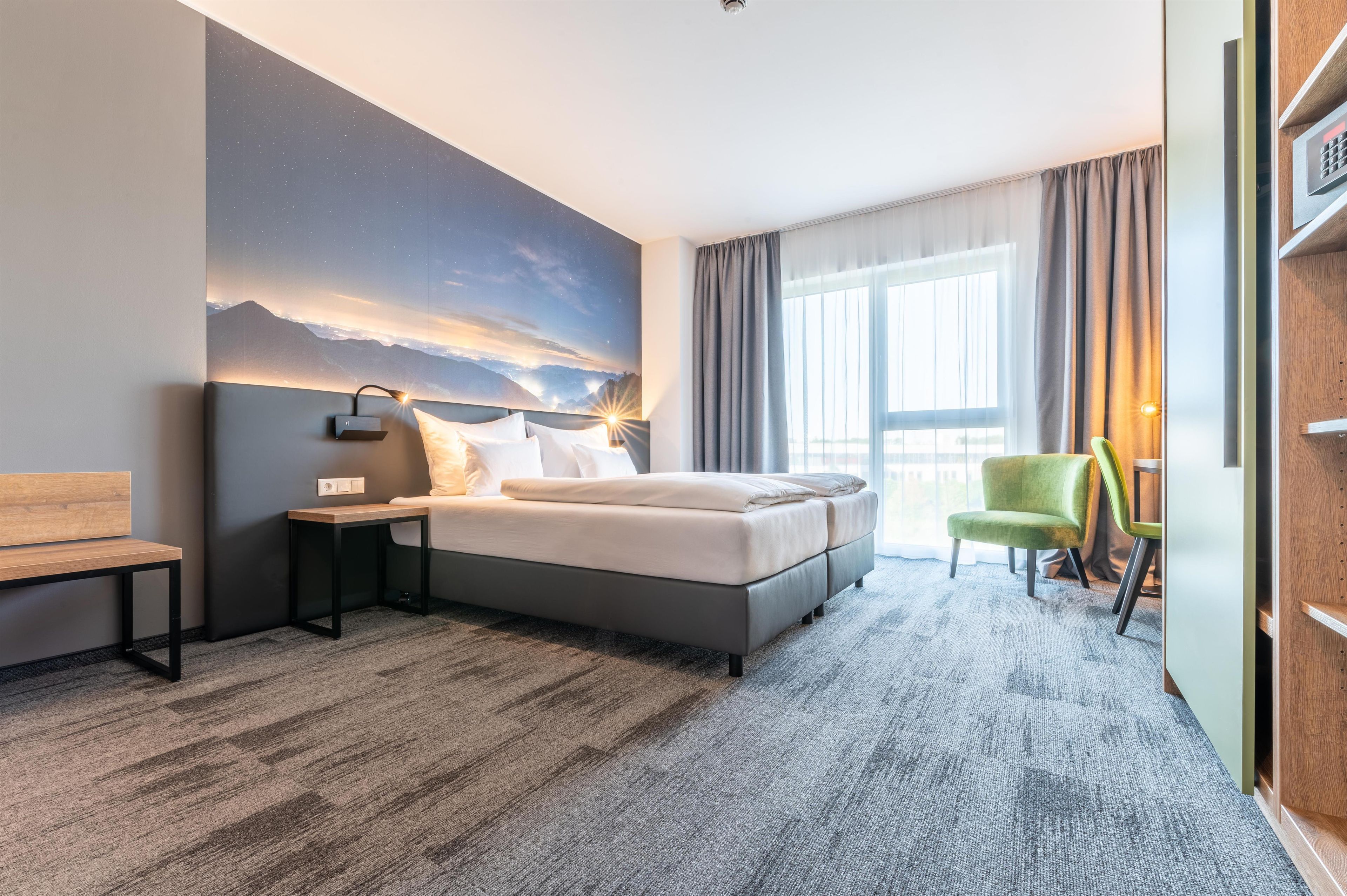 Une chambre d’hôtel moderne, dotée d’un grand lit, d’un bureau, d’une chaise et offrant une vue sur l’extérieur.