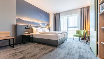 Une chambre d’hôtel moderne, dotée d’un grand lit, d’un bureau, d’une chaise et offrant une vue sur l’extérieur.