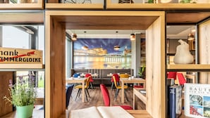 A modern interior with wooden furniture, a mural of a cityscape, and a sign that reads "thank ZIMMERGLOCKE". - Aiden by Best Western Stadtgut Hotel Steyr (Steyr)
