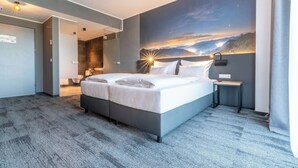 A modern hotel room with a large bed, a night sky mural, a small bedside table, and a view of the bathroom. - Aiden by Best Western Stadtgut Hotel Steyr (Steyr)
