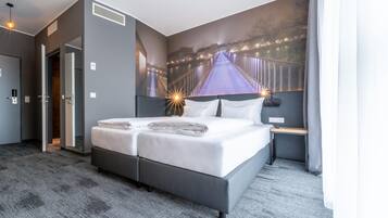 A hotel room with a large bed, a nightstand, a wall-mounted TV, and a door leading to another room.