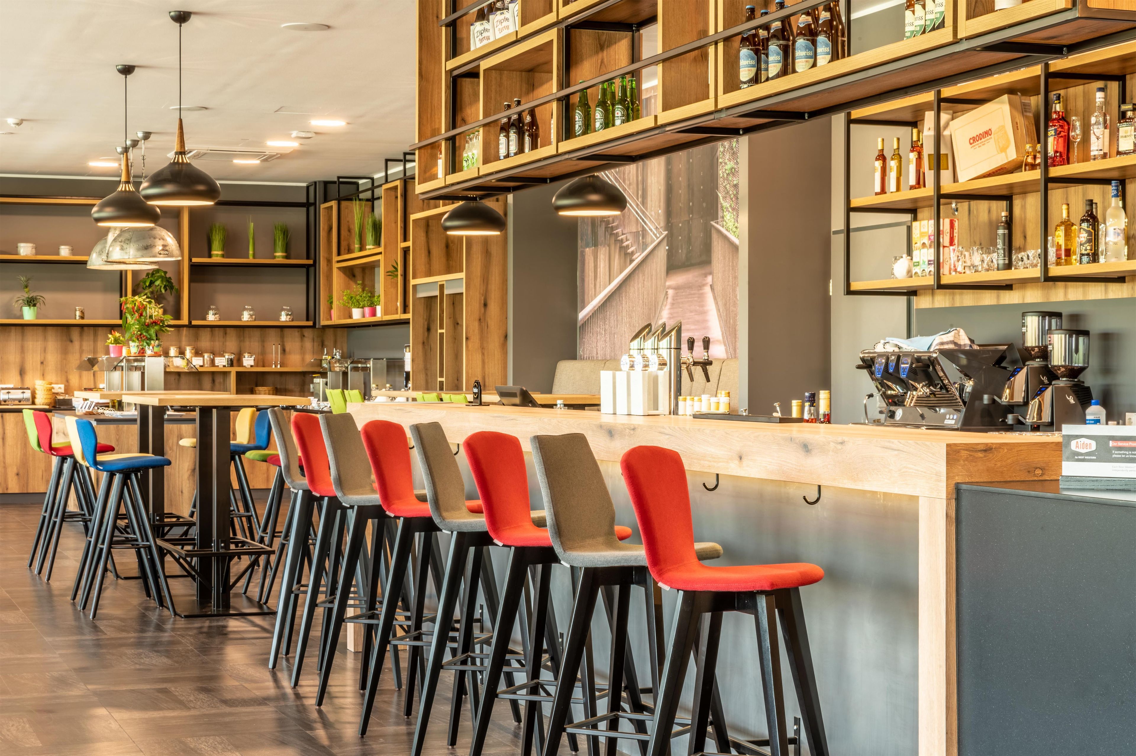 A bar area with multiple stools, a counter, and shelves with bottles.